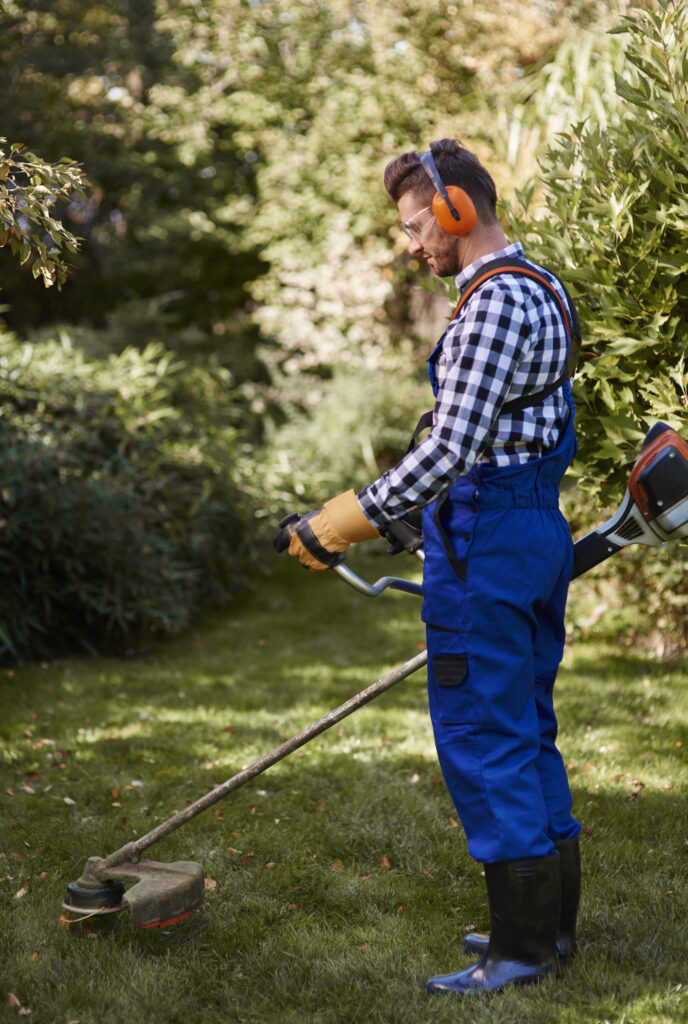 busy man using a weedwacker at garden